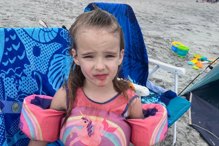 A 5 years-old girl posing for a photo on the beach.