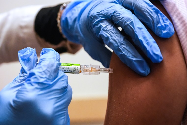 Gloved hands administer a flu shot to someone's arm