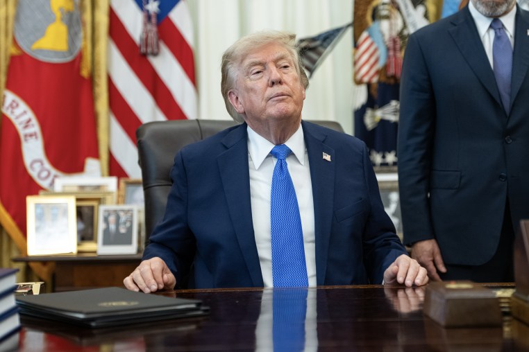 Donald Trump seated at his office in the Oval Office.