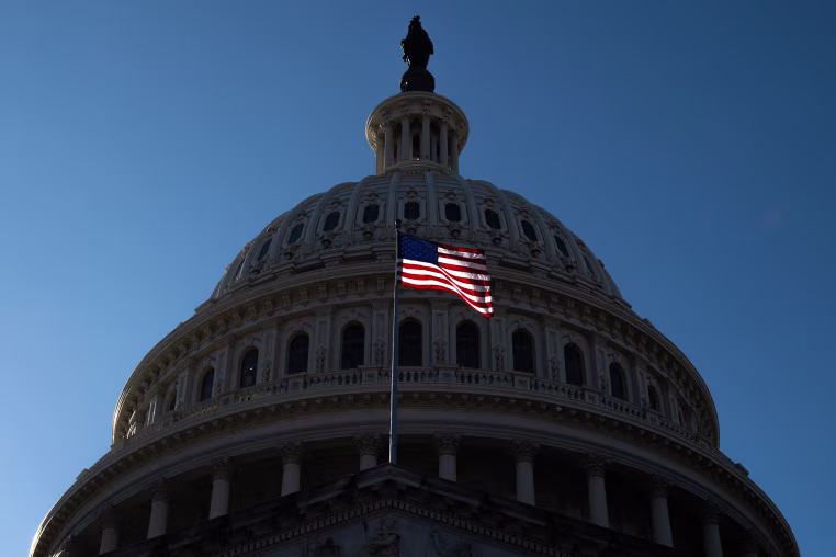 A U.S. flag flies in front of the dome of the Capitol.