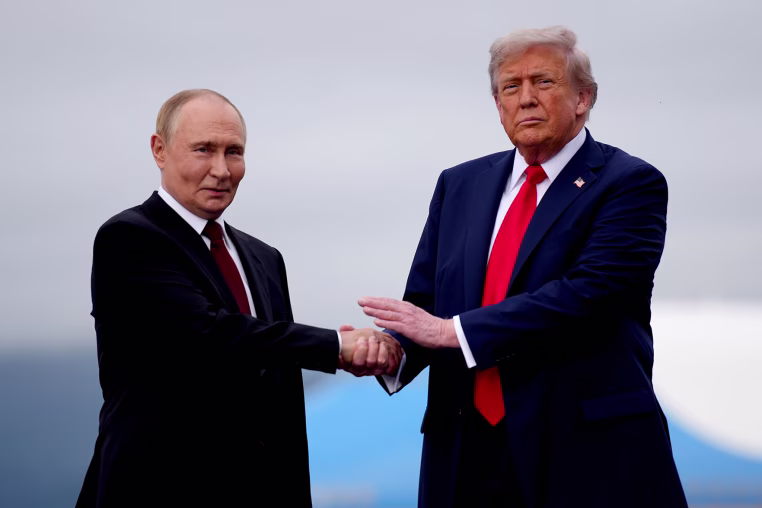 Putin, left, and Trump shake hands while standing outside