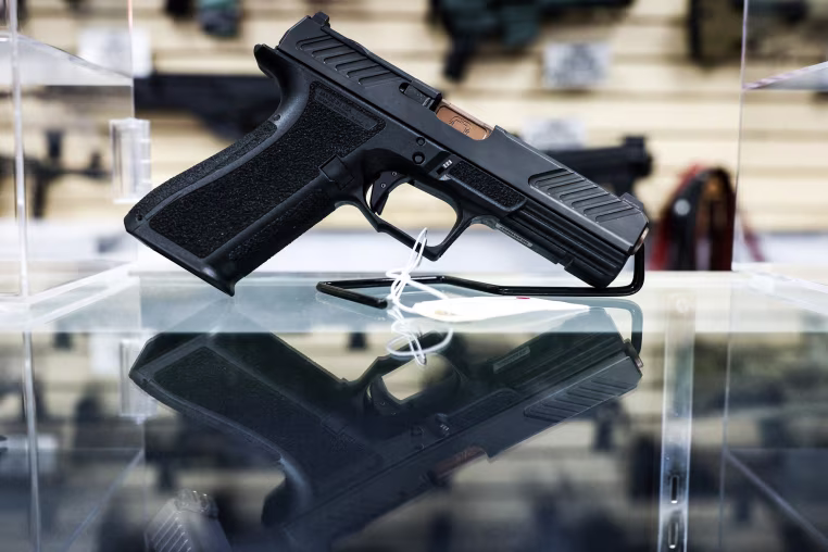 A shadow system pistol is displayed for sale in a gun store behind glass