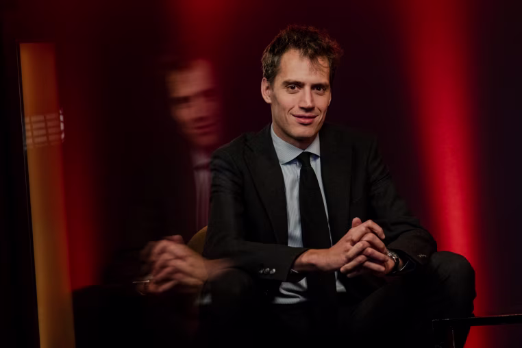 Arthur Mensch sits on a chair to pose for a portrait
