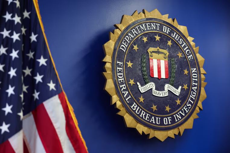 The logo of the Federal Bureau of Investigation hung on a blue wall next to an American flag