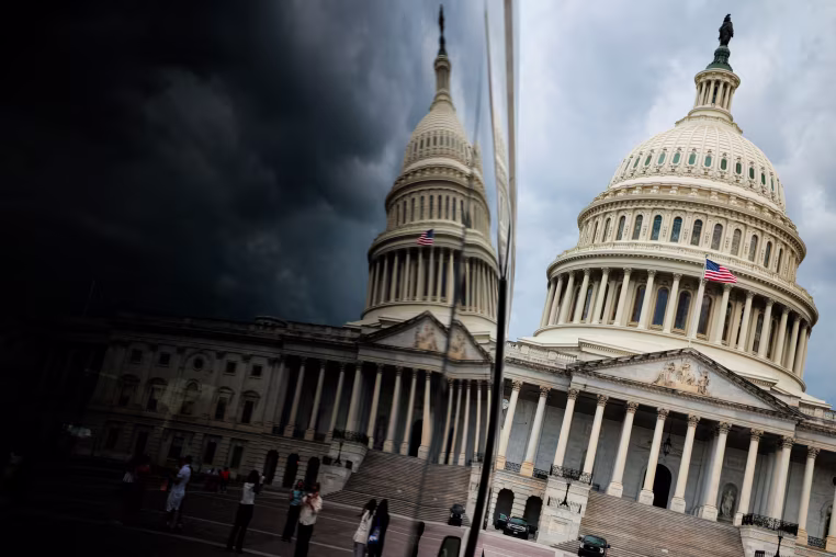 The exterior of the U.S. capitol building is reflected on a surface seen on the left
