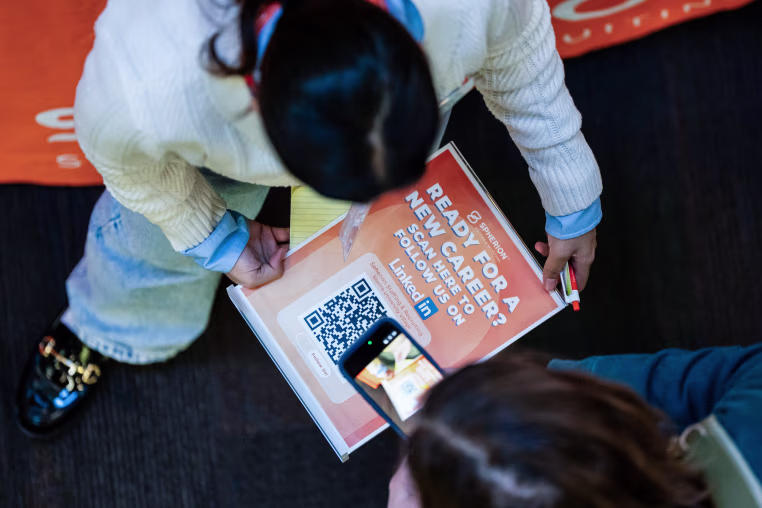A person appears to scan a QR code from an A4 sheet.