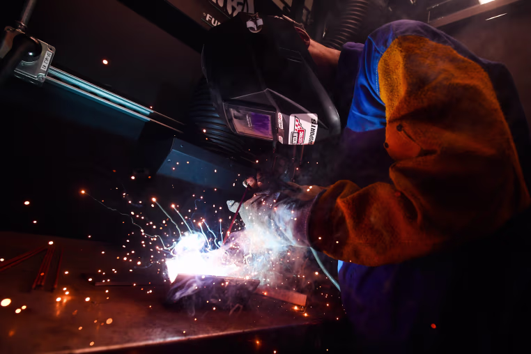 A person appears to be welding while wearing protective clothing.
