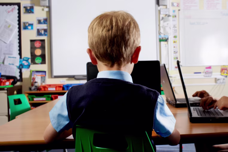 Young student in classroom using laptop  