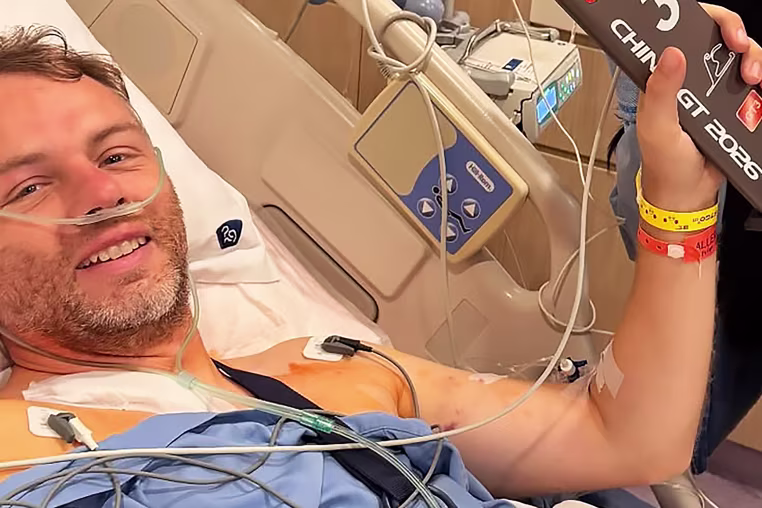 Image: Ollie Millroy lying in a hospital bed, wearing a nasal cannula.