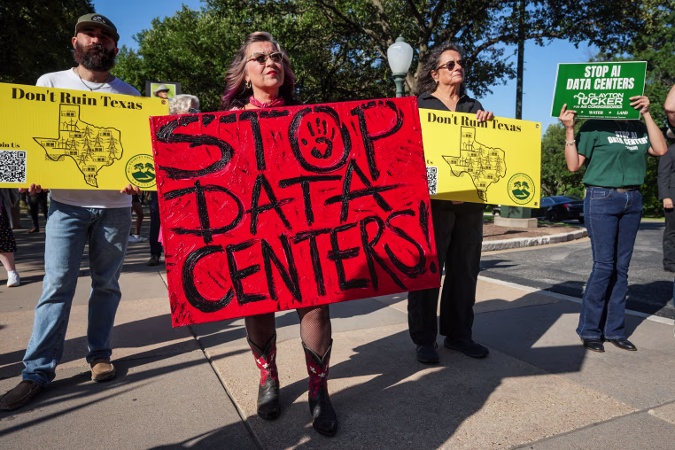 People hold anti-AI data center signs while protesting outside