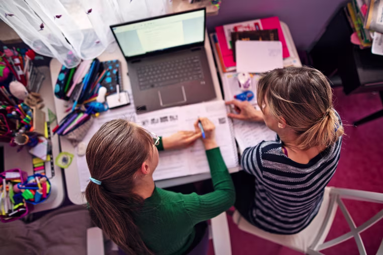 Image: Mother is helping daughter with homework in her room.