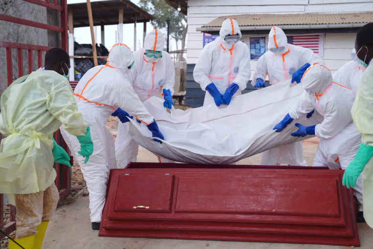 Health workers who are members of the safe and dignified burial team prepare to bury a person.