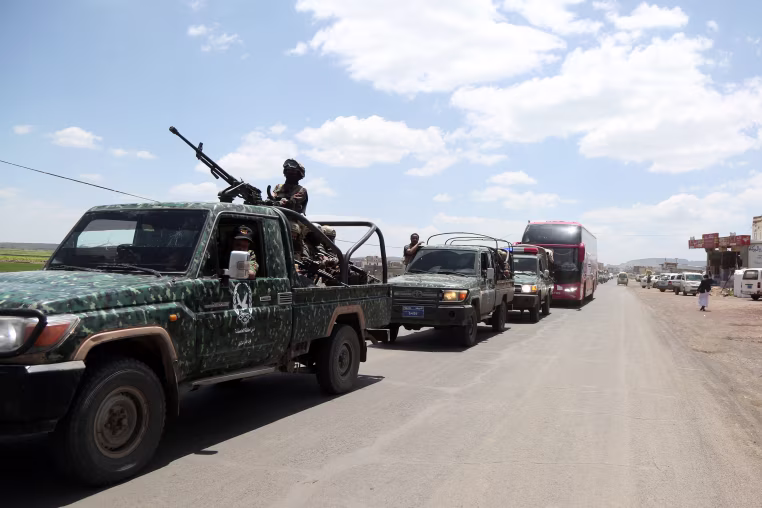 Yemeni security forces escort buses carrying released Houthi-aligned detainees as they arrive in Sana'a on September 12.