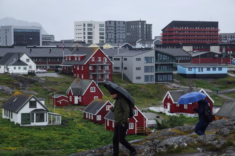 People with umbrellas walk in the rain in Nuuk.