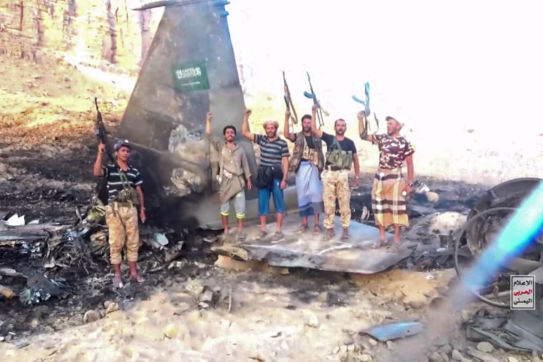 Houthi fighters stand in front of what they say is a downed Saudi jet, at a location given as Yemen