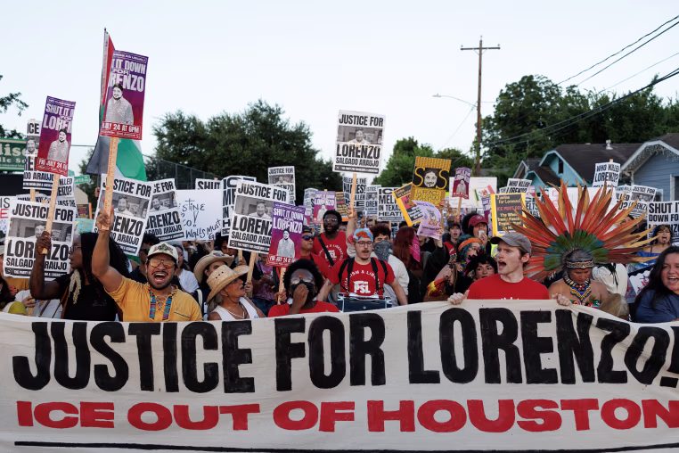 A crowd of protestors standing behind a banner reading JUSTICE FOR LORENZO! ICE OUT OF HOUSTON