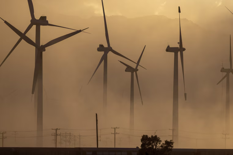 Wind turbines are partially obscured by a dust storm.