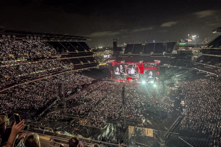 A wide shot of an outdoor stadium concert at night.