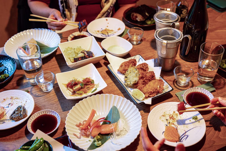 A top-down view of a crowded dining table at a Japanese restaurant.