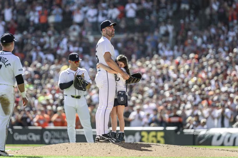 Justin Verlander hugs his daughter on the pitching mound in front of a stadium full of fans.