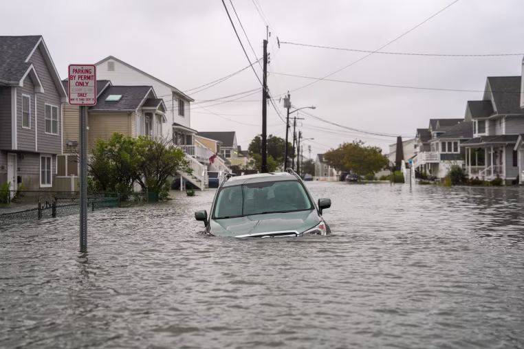 A car is seen submerged in water on a flooded road.