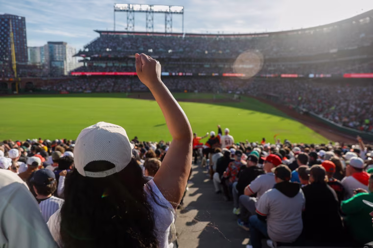 A woman cheers from the stands during a major league baseball game.