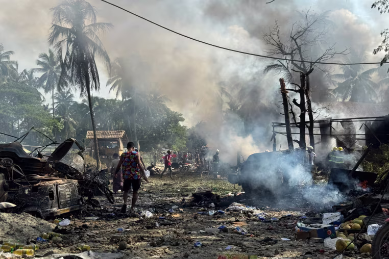 People walk through smoke and debris.