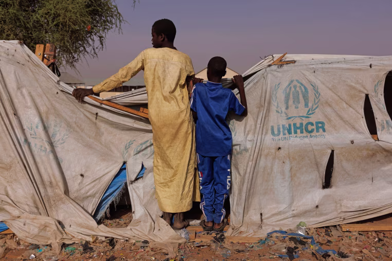 wo boys peer over a UNHCR aid tent at a camp in Chad for refugees from Darfur in Sudan