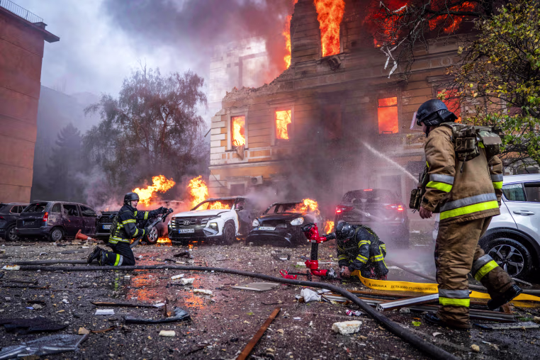 Firefighters aims hoses spraying water at a damaged building on fire