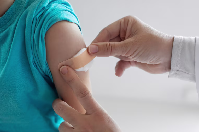 Unrecognizable doctor putting a patch on shoulder after successful vaccination