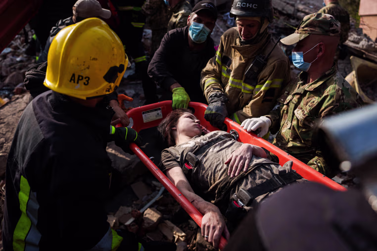 Rescuers carry a woman on a stretcher outside