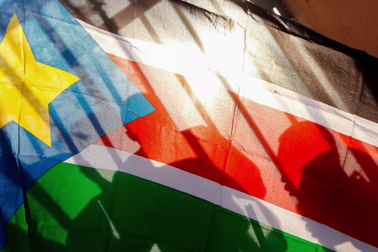 Silhouettes through a South Sudanese flag.
