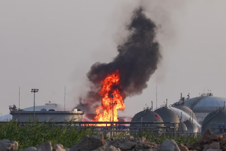 Flames burn at a facility outside in the distance