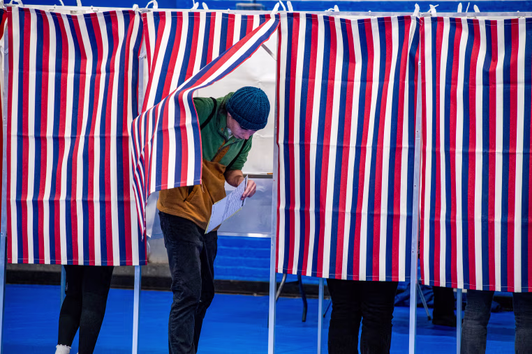 A person exits a voting booth after filling out their ballot.