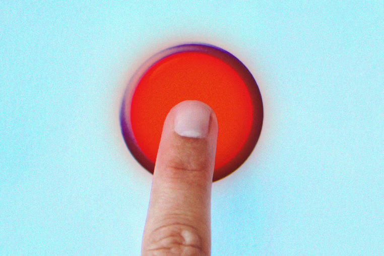 Photo illustration of a human finger pressing a large, glowing red button.