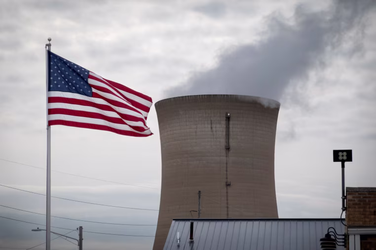 A cooling tower is seen next to an American flag.