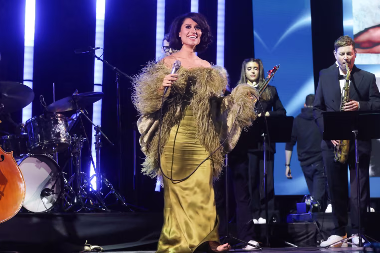 Image: Raye on stage holding a microphone.