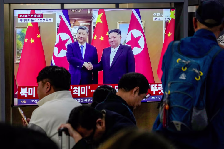A TV screen shows a file image of North Korean leader Kim Jong Un and Chinese President Xi Jinping.