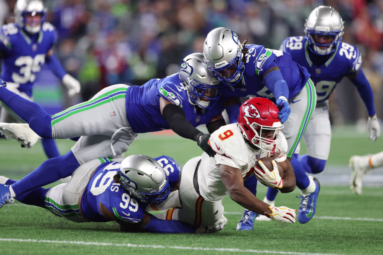 Kansas City Chiefs running back Kenneth Walker III is tackled by Leonard Williams, Uchenna Nwosu and Tyrice Knight of the Seattle Seahawks at Lumen Field on Sunday night. 