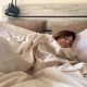 Woman sleeping in bed with white sheets
