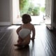 Rear view of baby boy wearing nappy crawling towards open front door