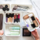 Overhead image of a Woman organizing her makeup, brushes and beauty items, in white storage containers
