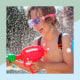 Little boy playing with a water gun outside