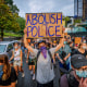 Image A participant holding a Abolish Police sign at a protest.