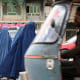 Image: Women wearing a burqa wait for a local taxi in Kabul