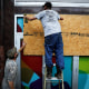 Men place plywood in front of a store in preparation for Hurricane Ida in New Orleans on Aug. 28, 2021.