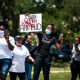 Demonstrators raise their fists at a parade of passing motorcyclists riding in honor of Ahmaud Arbery at Sidney Lanier Park on May 9, 2020, in Brunswick, Ga.
