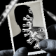 Photo illustration: A hand holding a photograph that shows the silouette of a person revealing a Covid spore. Blurred vaccine syringes float around it.