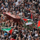Image: Mourners wave national flags as they carry the casket during a funeral procession.