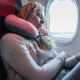 A female passenger sleeping on neck cushion in airplane.